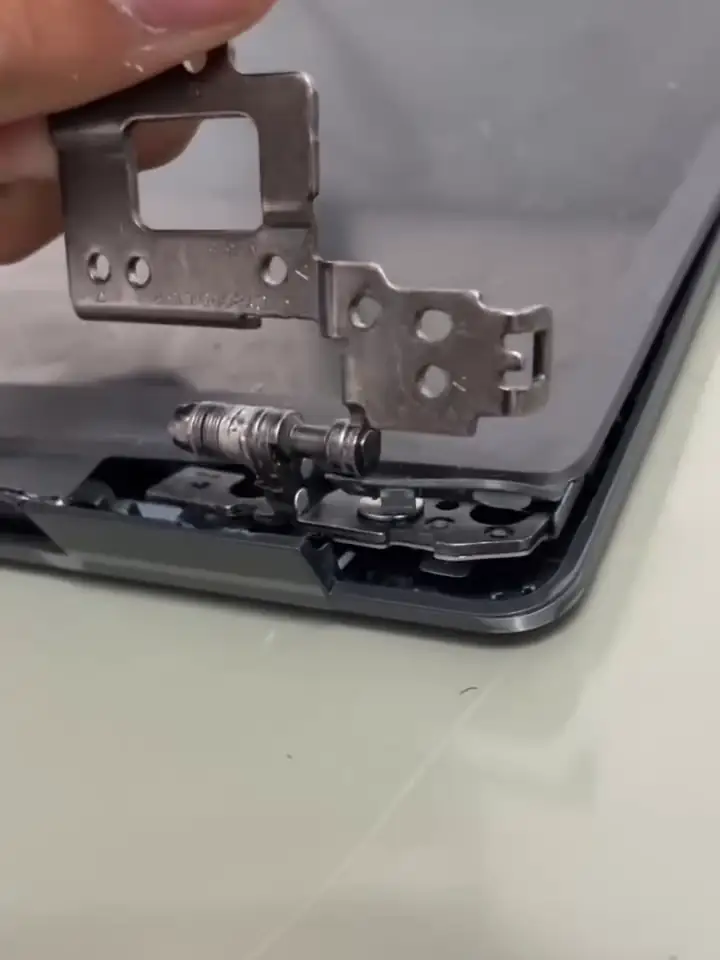 A dobradiça do notebook na mão, em cima da tampa