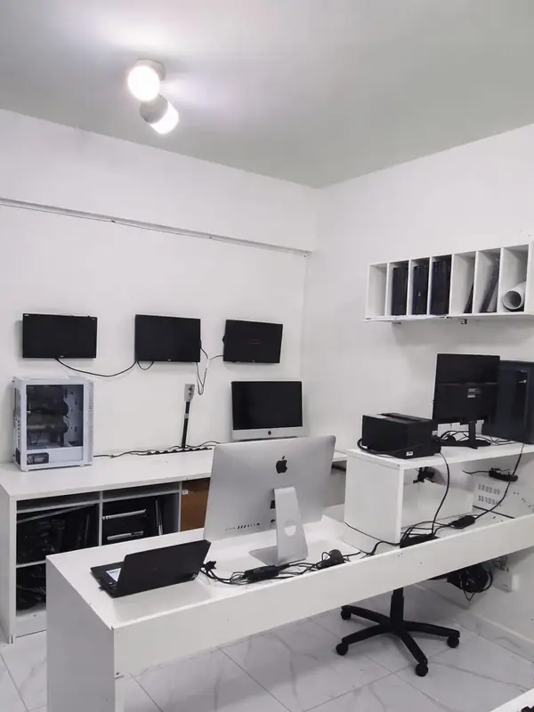 Laboratório da SSTech: bancadas brancas, monitores na parede e computadores nas mesas